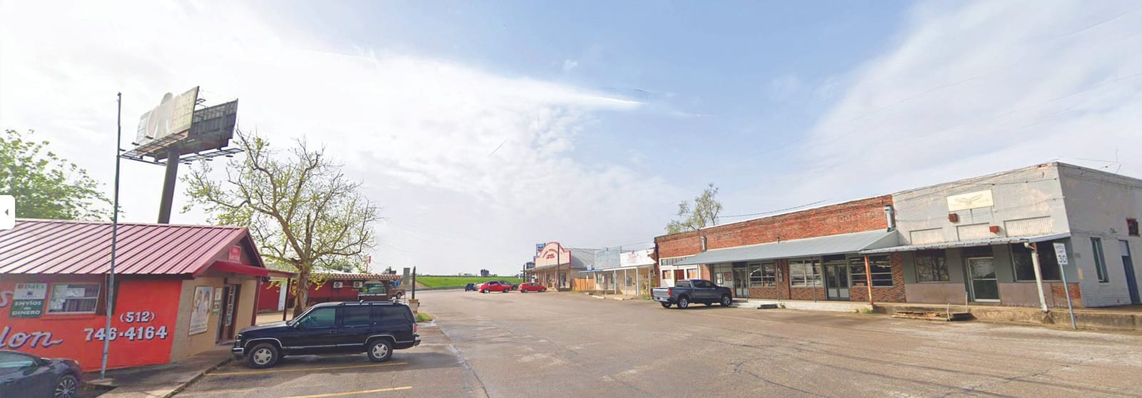 A wide view of a quiet Old Town street in Jarrell lined with low brick storefronts and parked vehicles