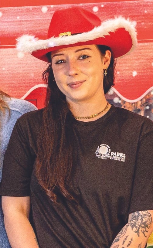 Young woman in a red cowboy hat with white fur trim and a black Parks & Recreation T-shirt.